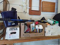 Shelf with blue tote, telescoping pole, cardboard boxes of cleaning bottles and brushes