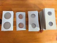 Four stacks of unfolded 2x2 cardboard coin flips displaying clear windows