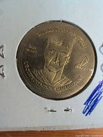 Obverse of brass coin in holder showing Rob Blake portrait and bilingual Olympic Team text