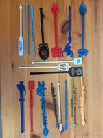 Full group of 18 assorted promotional cocktail stirrers on table