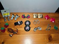 Full view of all 13 earring pairs arranged on wooden surface