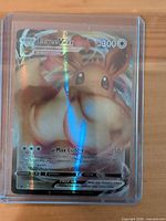 Front of Eevee VMAX card inside top-loader showing artwork, HP and holographic foil