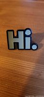 Front view of mint green "Hi." enamel lapel pin