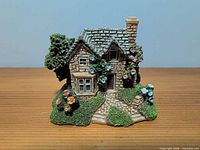 Front view of Lilliput Lane cottage figurine showing stone walls, windows, garden flowers