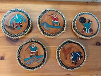 Five woven seagrass coasters with Inuit designs displayed on tabletop