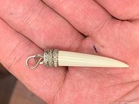 Full view of horn pendant front side showing tapered point and filigree cap