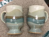 Two Otagiri stoneware footed mugs front view showing glaze bands and handles