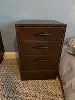 Front view of dark brown three-drawer nightstand