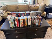 Two rows of assorted VHS tapes on a black coffee table