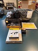 Complete Nikon D5200 kit with camera, accessories, box, bag and paperwork displayed on table