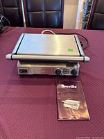 Front view of grill closed, user manual beside unit