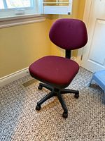 Full view of burgundy fabric office chair showing seat, backrest and base