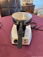 Front view of waffle maker showing handle, top lid with Cuisinart logo and control panel