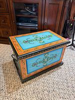 front angled view of painted wood chest showing floral artwork and side handle