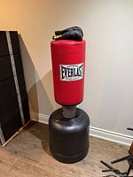 Full view of Everlast red heavy bag on black base with gloves on top