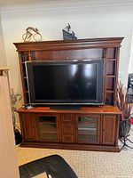 Front view of full entertainment wall unit with TV for scale (TV not included) showing upper hutch, side shelves, base cabinet