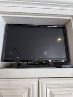 Front view of RCA 32-inch TV on stand inside cabinet