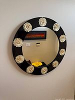 Front view of round black mirror with mother-of-pearl flower accents