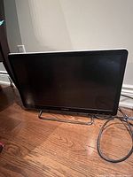 Front view of Sony NSX-24GT1 TV on chrome stand with attached cable visible