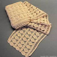 Rolled length of ecru crocheted lace showing full width