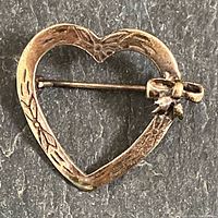 Front view showing heart shape, etching, bow, pin mechanism