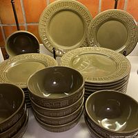 Stacked set showing dinner plates, luncheon plates, cereal bowls, serving bowl in avocado green glaze