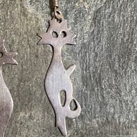 Close-up of single cat earring showing shape, cut-outs and metal finish