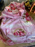 Full view of tablecloth draped, showing pink rose pattern and striped border