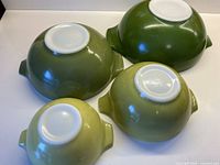 Bottom view of all four nested Pyrex Verde bowls showing graduated sizes and color shades