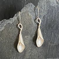 Full view of both sterling silver calla lily earrings on dark background