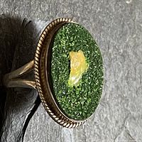 Full view of ring showing oval green crystal face with opal centre