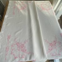 Full view of folded white linen tablecloth showing embroidery layout