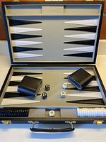 Open backgammon case showing board, dice cups, dice, doubling cube and stacked checkers