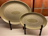 Both oval platters on stands showing full size comparison and overall pattern