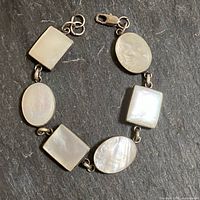 Full view of sterling silver bracelet showing alternating oval and rectangular mother-of-pearl links and clasp