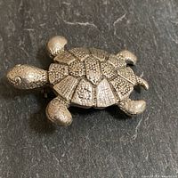 Oblique view of sterling silver turtle brooch showing texture and form