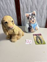 Front view of cement dog statue, door-stop pillow and sealed nail clippers