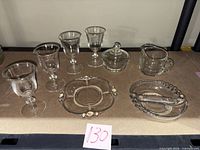 All eight glass pieces displayed: four stemmed glasses, lidded sugar bowl, creamer, round divided dish with beaded rim, oval beaded dish