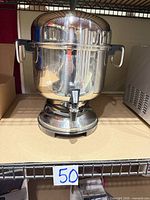 Front view of Farberware stainless electric coffee urn on shelf