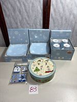 Full lot view showing boxed plates, boxed mugs, snowman plate box, gift tag packs