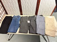 Six pairs women’s pants laid flat showing colors and styles