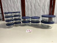 All fourteen glass bowls with blue lids arranged by size