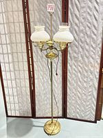 Full view of the brass-tone metal floor lamp standing upright