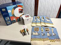 Boxed dinnerware set, boxed spreader set, four loose spreaders, stack of towels