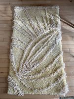 Full view of rectangular hand-hooked cream rug on wood floor