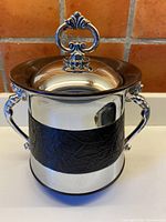 Full view of chrome ice bucket showing vinyl band, both figural handles and lid