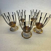 Five liqueur glasses front view showing black stripes and gold bases