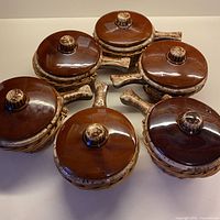 Six covered brown drip soup bowls nested in wicker holders