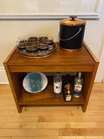 Front view of teak table showing top surface and lower shelf