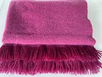 Folded fuchsia mohair-wool blanket with fringe visible